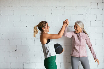 Happy women in sportswear celebrating success in gym