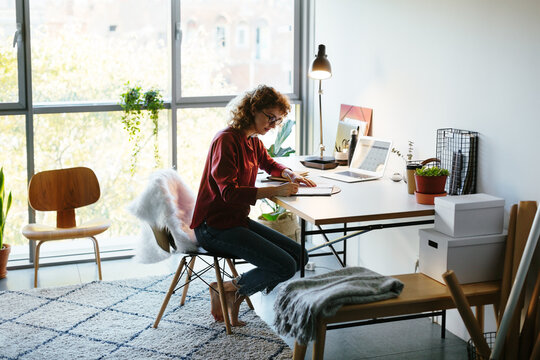 Barefoot freelancer making notes in notepad