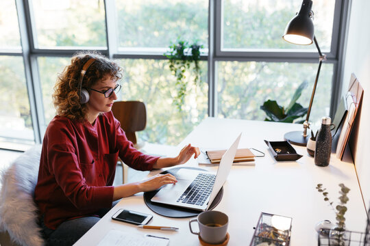 Female freelancer listening to music and using laptop