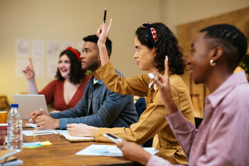 Multiracial coworkers having meeting and voting with raised hands
