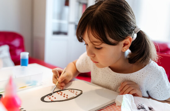 Little girl drawing Easter eggs