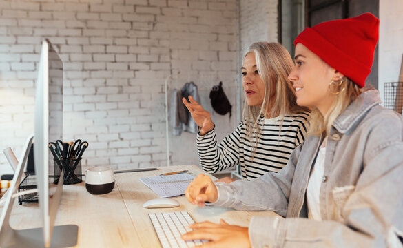 Mature designer explaining data to colleague - Powered by Adobe