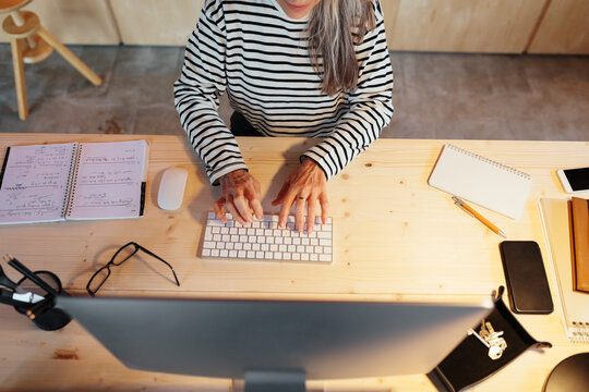 Crop woman using computer in office in evening
