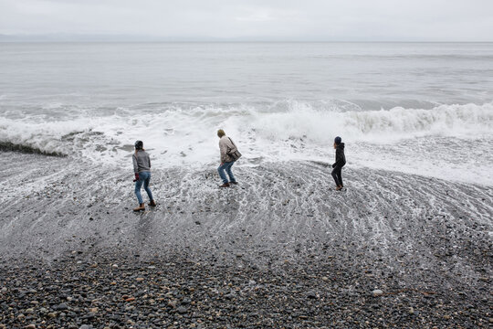 Fun grandpa playing with grandkids on rugged beach in winter.