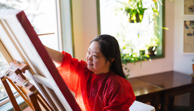 Young woman painting at home.