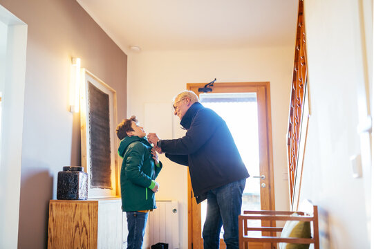 Grandfather helping boy to zip outwear