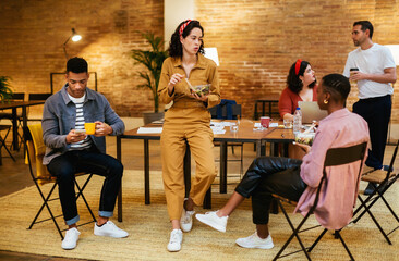 Young busy people having lunch and talking at workplace
