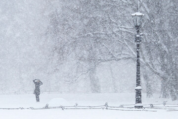 Snowstorm. Girl in the city park. Heavy snow in the city Park. Winter background.