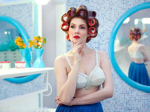 Portrait of vintage styled woman in a mid-century bathroom, with hair curlers in her hair.