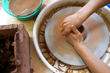 Potter's hands behind the potter's wheel. The manufacture of pottery.