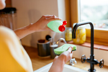 Crop person pouring detergent on sponge