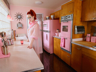 Vintage styled portrait of woman lost in thought in a mid-century style kitchen. 