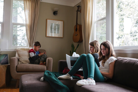 Kids using screens on couch at home. Technology tablets and computers at home.