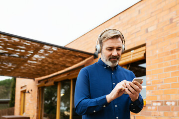 Adult man listening music and using smartphone.