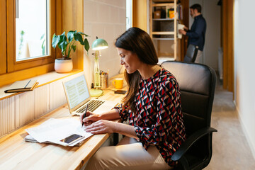 Female freelancer making notes near husband