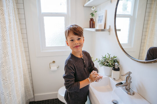 Young boy washing hands in bathroom at home.