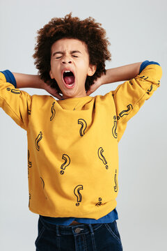 Ethnic kid yawning at camera in studio