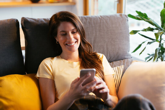 Adult woman using Smartphone on a sofa.