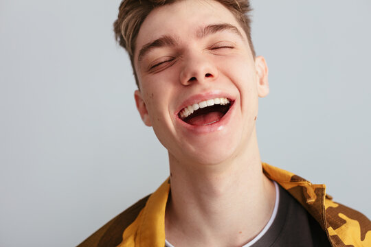 Happy teenager with acne laughing with eyes closed
