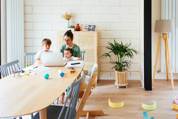 Mother with children using laptop at messy home