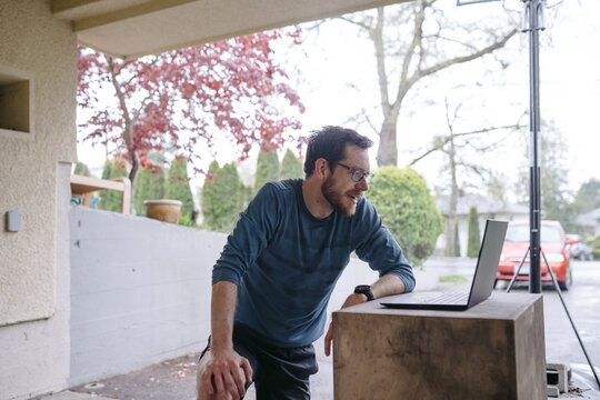Sweaty, fit man using laptop computer in the carport after hard