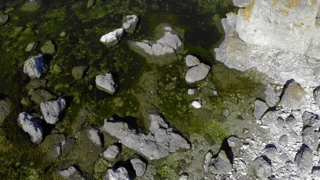 Aerial view over Rauk rocks, on the coast of Faro island, on a tranquil, summer day, in Gotland, Sweden - top down, drone shot