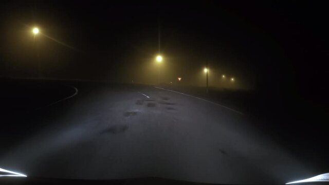 Driving down empty road at night in thick fog