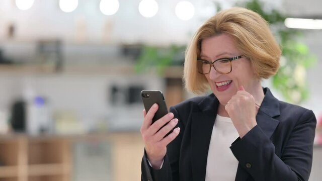 Portrait of Excited Old Businesswoman Celebrating Success on Smartphone 