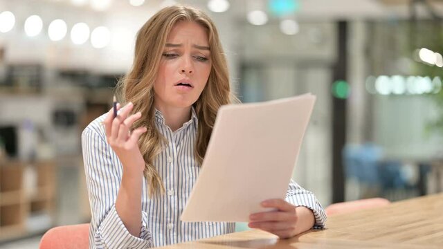 Disappointed Businesswoman Reading Documents in Office 