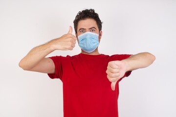 Young caucasian man with short hair wearing medical mask standing over isolated white background...