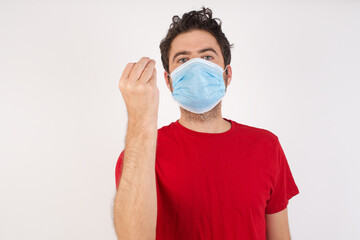 Young caucasian man with short hair wearing medical mask standing over isolated white background angry gesturing typical italian gesture with hand, looking to camera
