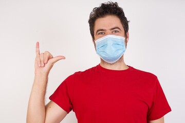 Young caucasian man with short hair wearing medical mask standing over isolated white background showing up number six Liu with fingers gesture in sign Chinese language