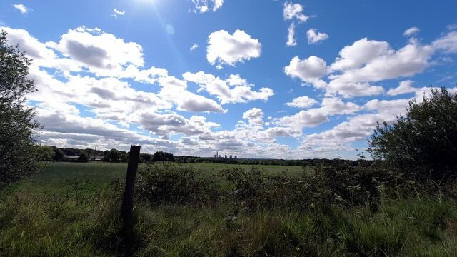 Countryside farmland timelapse meadow with fast moving clouds casting shadows on ground on sunny day
