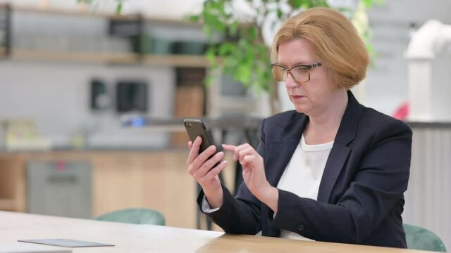 Serious Businesswoman using Smartphone in Office 