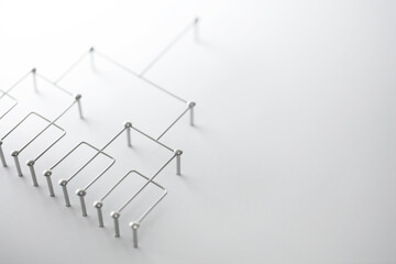 Hierarchy, command chain, company / organization structure or layer and grouping concept image. Top down structure made from chrome wires and silver nails and wire on white. Shallow depth of field.