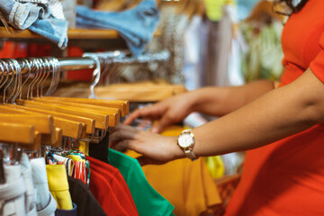 Detalle manos de joven mujer mexicana buscando ropa en tienda boutique aparador