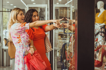 Amigas viendo ropa en aparador de tienda comercial