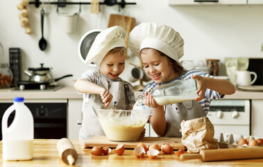 Happy siblings preparing food in kitchen.