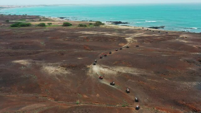 Aerial shot of a quad bikes driving through the rough terrain, during an off road adventure,close to the coastline.