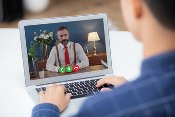 Fototapeta na wymiar Young asian businessman video conference and discussion with businessman, man work from home with laptop computer with social distancing, meeting online, communication and business concept.