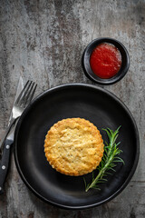 Merat Pie on Black Plate with Rosemary and Tomato Sauce