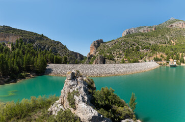 Naklejka premium Summer with blue sky in Castilles in Spain. View of the dam of Lake Taibilla with an imposing rock in the foreground. The pump station is on the right.