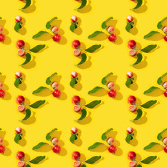 Seamless regular creative pattern from ripe small red apples and green leaves on yellow color