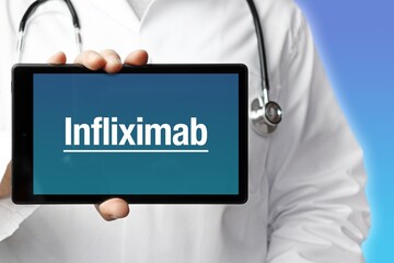 Infliximab. Doctor holds a tablet computer in his hand. Close up. Text is on the display. Blue Background