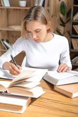 Concentrated young female student doing homework and preparing for exams