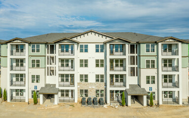 Elevated view of newly constructed apartment condo building with light green and white panels small balcony Alpine style roof and dreamy sky near Frederick Maryland USA