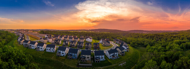 Aerial view of sunset with orange, yellow, red sky over a new American single family large real estate suburban  neighborhood in the East Coast
