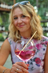 Portrait of mature woman sitting in a backyard holding glass with gin and tonic