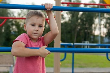 Fototapeta na wymiar a little boy doing rock climbing on a Playground on a summer day. games on fresh air