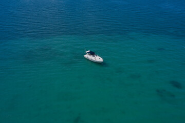 The boat is standing on shallow water. Yacht on blue water. Top view of the boat. Aerial view luxury motor boat.